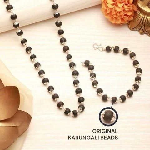 Black beaded necklace and bracelet set on a light background with decorative elements.